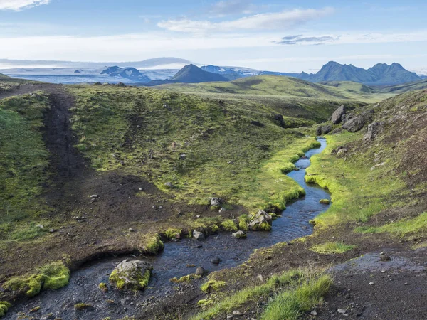 Volcanic landscape with mountains of Tindfjallajokull glacier massif, green hills and blue creek water with lush moss. Fjallabak Nature Reserve, celand. Summer blue sky — Stock Photo, Image