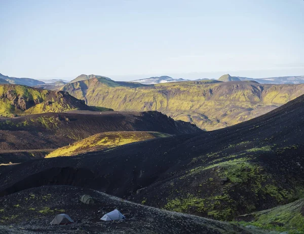 Trzy namioty samotnie w Botnar campingu na Islandii na Laugavegur szlaku turystycznym, zielona dolina w krajobrazie wulkanicznym wśród pól lawy z widokiem na lodowiec Myrdalsjokull. Wczesnym rankiem świt — Zdjęcie stockowe