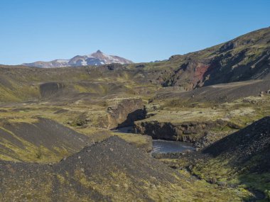 Icelandic landscape with blue Markarfljot river canyon, green hills and Tindfjallajokull glacier mountain peak. Fjallabak Nature Reserve, Iceland. Summer blue sky