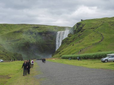 İzlanda, Skogar, 4 Ağustos 2019: Skogar 'da renkli giyinmiş bir grup turist ile Skogafoss Şelalesi' nde güzel bir şelale. Güney İzlanda.