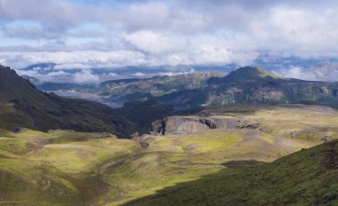 Godland manzarası panoramik nefes kesen manzara ve engebeli yeşil yosun kaplı kayalar ve tepeler, bükücü nehir kanyonu, İzlanda, Fimmvorduhals yürüyüş yolu. Yaz bulutlu günü.