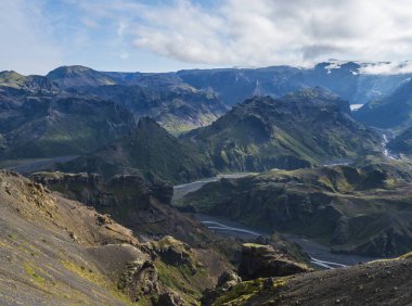 Godland ve Thorsmork 'un engebeli yeşil yosun kaplı kayalar ve tepeler, nehir kanyonu, İzlanda, Fimmvorduhals yürüyüş yolu. Yaz mavi gökyüzü beyaz bulutlar