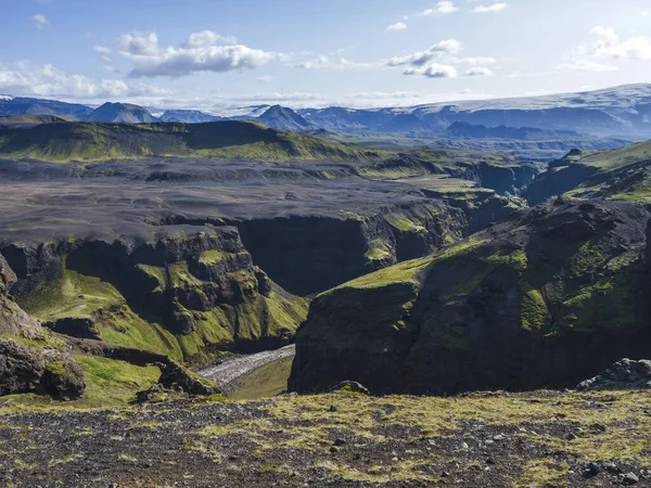 Widok na majestatyczny wąwóz kanionu Markarfljotsgljufur, rzekę i język lodowca Tindfjallajokull i zielone wzgórza. Rezerwat przyrody Fjallabak, Islandia. Lato błękitne niebo, chmury. — Zdjęcie stockowe