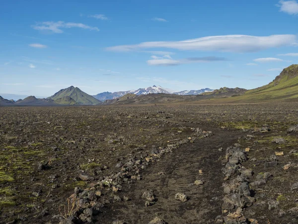 Islandská lávová pouštní krajina s pěšinou Laugavegur turistické stezky s výhledem na Tindfjallajokull ledovcové hory a zelené kopce. Přírodní rezervace Fjallabak, Island. Letní modré nebe — Stock fotografie