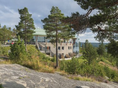 UTANSJO, SWEDEN - August 21, 2019: view on rounded building of Hotel Hoga Kusten between pine trees next High coast bridge Hogakustenbron