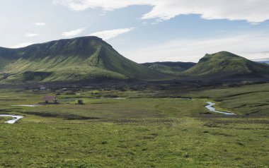 view on Hvanngil mountain hut and camp site with green hills, river stream and lush grass and moss. Laugavegur hiking trail, Fjallabak Nature Reserve, Iceland. Summer blue sky