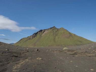 Volcanic desert landscape with green Hattafell mountain with footpath of Laugavegur trail. Fjallabak Nature Reserve, Iceland. Summer blue sky