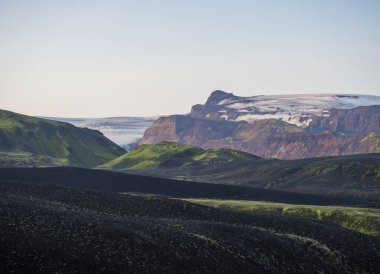 Sunrise at Botnar campsite at Iceland on Laugavegur hiking trail, green valley in volcanic landscape with view on Myrdalsjokull glacier. Early morning pink light