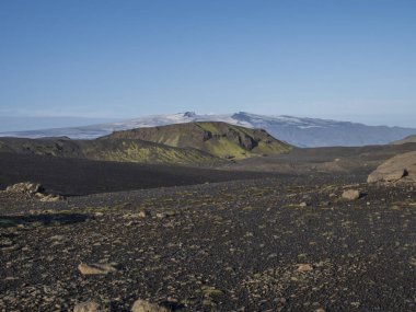 Icelandic landscape with eyjafjallajokull glacier tongue, blue river stream and green hills. Fjallabak Nature Reserve, Iceland. Summer blue sky