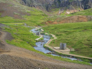 Reykjadalur Vadisi 'nde, tahta patikalı ve soyunma odalı bir sıcak nehir deresinde doğal jeotermal banyo. Güney İzlanda, Hveragerdi şehri yakınlarında. Yaz güneşli sabah