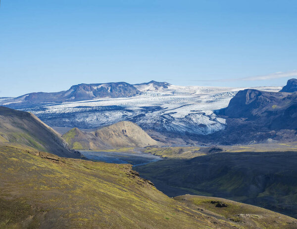 Icelandic landscape with eyjafjallajokull glacier tongue, Markarfljot river and green hills. Fjallabak Nature Reserve, Iceland. Summer blue sky