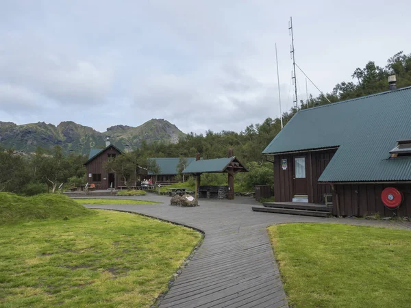 ICELAND, THORSMORK, 3 de agosto de 2019: Casa de campo de madera de la cabaña de montaña de Basar y camping con prado de hierba, paseo marítimo y bosque de abedules. Inicio de la ruta de senderismo Fimmvorduhals . — Foto de Stock