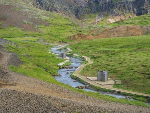 Reykjadalur Vadisi 'nde, tahta patikalı ve soyunma odalı bir sıcak nehir deresinde doğal jeotermal banyo. Güney İzlanda, Hveragerdi şehri yakınlarında. Yaz güneşli sabah