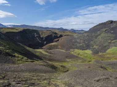 Görkemli Markarfljotsgljufur Kanyon vadisi ve nehir üzerinde yeşil yosun kaplı tepeler İzlanda 'nın dağlık kesimlerindeki Fjallabak Doğa Koruma Alanı' nda Botnar kampı yakınlarında, mavi gökyüzü arka planı