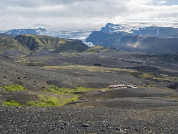 Cabane de montagne Botnar et camping sur le sentier de randonnée Laugavegur, vallée verdoyante dans un paysage volcanique au milieu des champs de lave avec vue sur le glacier Myrdalsjokull. Journée ensoleillée d'été, ciel bleu . — Photo