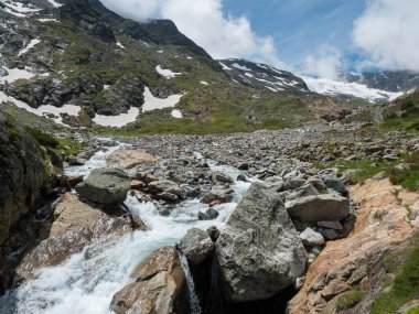 Karla kaplı dağ tepeleri ve vahşi Freigerbach akıntısı ile dağlık arazinin yaz manzarası. Tyrol, Stubai Alpleri, Avusturya