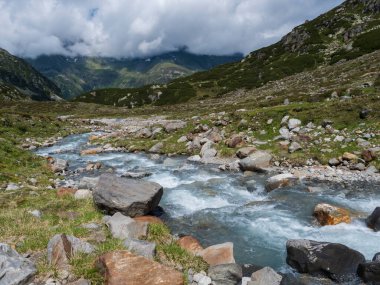 Karla kaplı dağ tepeleri ve vahşi Freigerbach akıntısı ile dağlık arazinin yaz manzarası. Tyrol, Stubai Alpleri, Avusturya