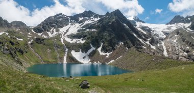 Yeşil çayır ve karla kaplı dağ tepeleri ile dağlık arazide turkuaz mavisi Grunausee Gölü panoramik manzarası. Tyrol, Stubai Alpleri, Avusturya, yaz güneşli gün