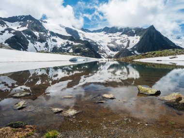 Eriyen buz buzulundan kaynaklanan pınarlarla dolu güzel bir buzul gölü. Keskin kar tepeleri su yüzeyine yansıyor. Tyrol, Stubai Alpleri, Avusturya, yaz güneşli gün