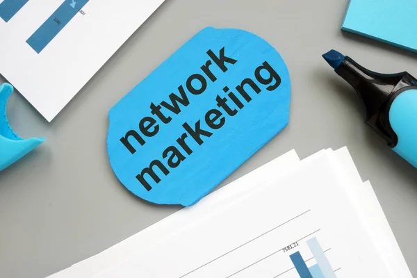 Text sign showing network marketing. The text is written on a small wooden board. Colored paper sheet, markers, wooden background are on the photo.