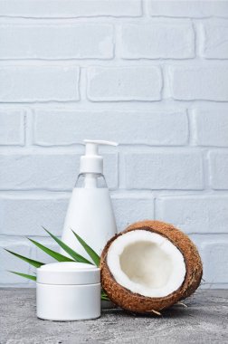 Boş beyaz mockup dağıtıcı şişe taze Hindistan cevizi ve gri beton zemin üzerine yeşil palmiye yaprağı ile kozmetik ürünleri
