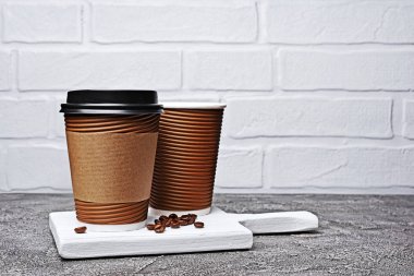 Eve servis boş kağıt kahverengi kahve fincanı siyah kapak, zanaat bardak tutucu ve gri beton zemin üzerine fasulye ile