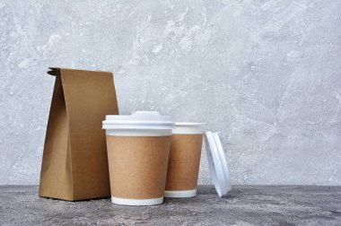 Beyaz kapakları, zanaat bardak tutucular ve gri beton zemin üzerine kahverengi paket paket servisi boş kağıt kahve bardağı