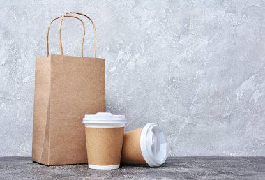 Beyaz kapakları, zanaat bardak tutucular ve gri beton zemin üzerine kahverengi paket paket servisi boş kağıt kahve bardağı