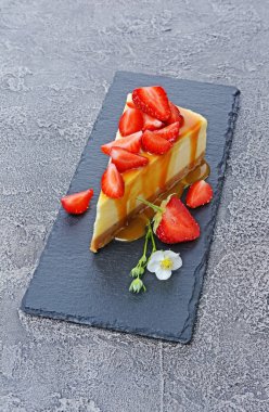 Lezzetli ev yapımı cheesecake taze çilek, bahar çiçekleri ve dilim cutboard Karamel sosu ile dilim yakın çekim