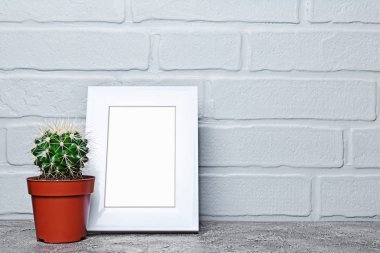 Kırmızı saksıyı küçük kaktüs ve mock-up kopya alanı için poster gri beton ve tuğla duvar arka plan üzerinde beyaz çerçevesi ile