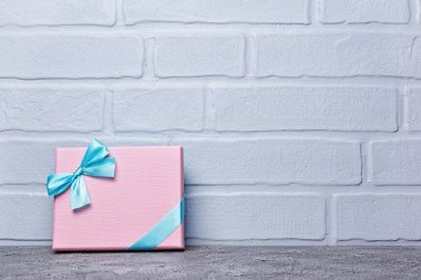 Tek pembe klasik hediye kutusu gri beton ve tuğla duvar zemin üzerine mavi saten yay ile