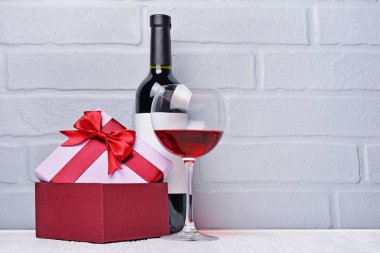 Kırmızı şarap tatma ve hediye kutusu gri tuğla duvar adam romantik sürpriz için cam