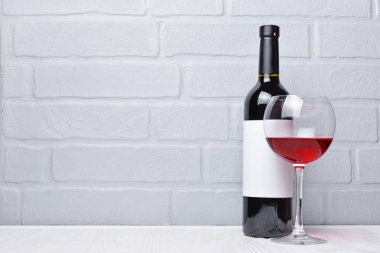 Boş etiket ve gri tuğla duvar arka plan üzerinde tatmak için cam ile kırmızı şarap şişesi