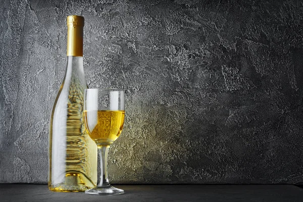 Beyaz şarap şişesi ve gri beton zemin üzerine koyu mahzende tatmak için cam