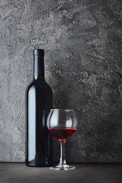 Kırmızı şarap şişesi ve gri beton zemin üzerine mahzende tatmak için cam