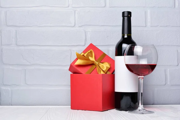 Glass with red wine for tasting and gift box for romantic surprise on gray brick wall backgroun