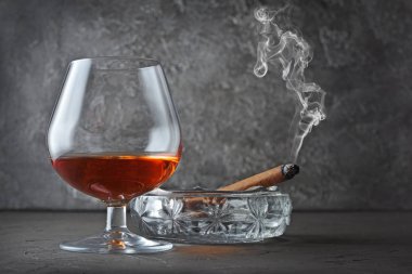 Güçlü alkollü içki konyak sniffer cam kristal kül tablası gri beton zemin üzerine yasaktır puro ile