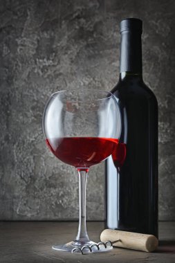 Kırmızı şarap şişesi ve tirbuşon gri beton zemin üzerine koyu mahzende ile tatmak için cam