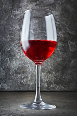 Gri beton zemin üzerine koyu mahzende tatmak için kırmızı şarap ile tek cam