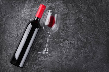 Yalancı kırmızı şarap şişe ve cam gri beton zemin üzerine tatmak için düz yatırın