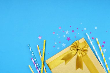 Altın parlak klasik hediye kutusu parti mavi zemin üzerine özniteliklerini olarak yıldız şeklinde konfeti ile kokteyl payet ve saten yayla