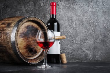 Cam gri beton zemin üzerine koyu mahzende tatma ve ahşap varil ile kırmızı şarap şişesi
