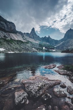 Peyzaj taşlar ve kayalar üzerinde dramatik bulutlu gökyüzü adam güzel yaz dağ Gölü