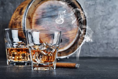 Güçlü alkollü içki scotch viski buz küpleri yasaktır puro ile eski moda bardaklarda ve gri beton zemin üzerine mahzende vintage ahşap varil ile