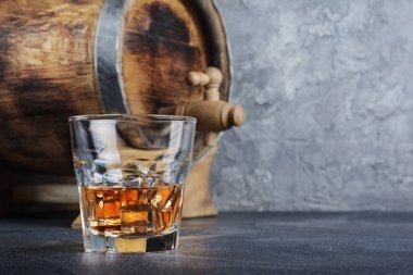 Güçlü alkollü içki scotch viski eski moda cam ve vintage ahşap varil gri beton zemin üzerine mahzende buz küpleri ile