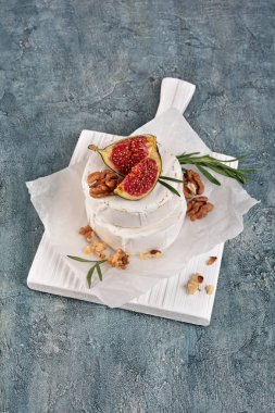 Taze incir, fındık ve biberiye baharat ahşap kesme tahtası ve gri beton zemin ile gurme meze beyaz brie peyniri veya camembert