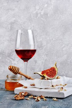 Taze incir, fındık, bal ve ahşap kesme tahtası ve gri beton zemin kırmızı şarap ile gurme meze beyaz brie peyniri veya camembert