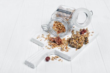 Sağlıklı kahvaltı ev yapımı granola ile fındık ve açık cam kavanoz ve enerji çubuğunda Beyaz ahşap tahta arka plan ayçiçeği tohumu