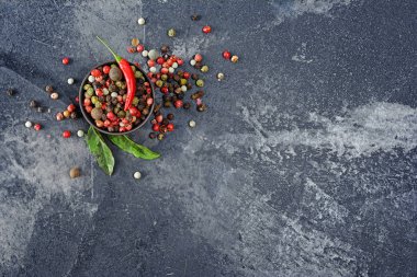 Kopya alanı karanlık beton zemin üzerine baharatlı karışımı farklı karabiber, kırmızı bakla ve fesleğen yaprakları