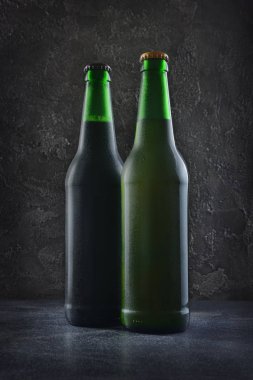 İki damla gri beton zemin üzerine soğuk karanlık ve aydınlık bira şişesi